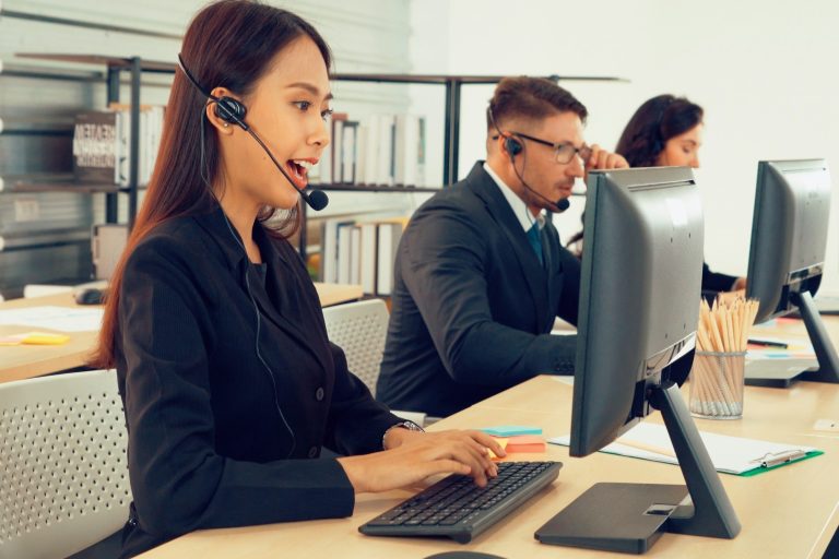 Trois agents de service client au travail avec des casques et des ordinateurs.