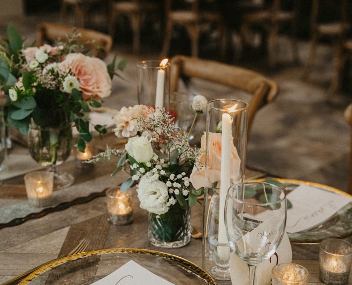 Vase de fleurs élégantes sur une table, avec chandelles et décor raffiné.