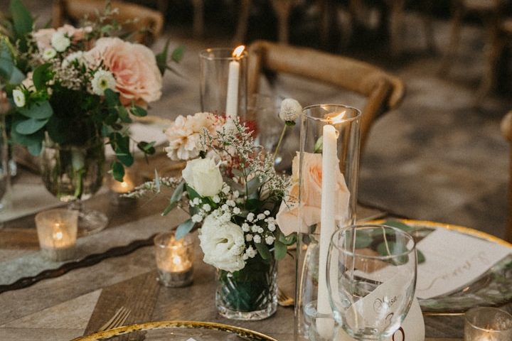Arrangement de fleurs avec bougies sur une table élégante, ambiance chaleureuse.