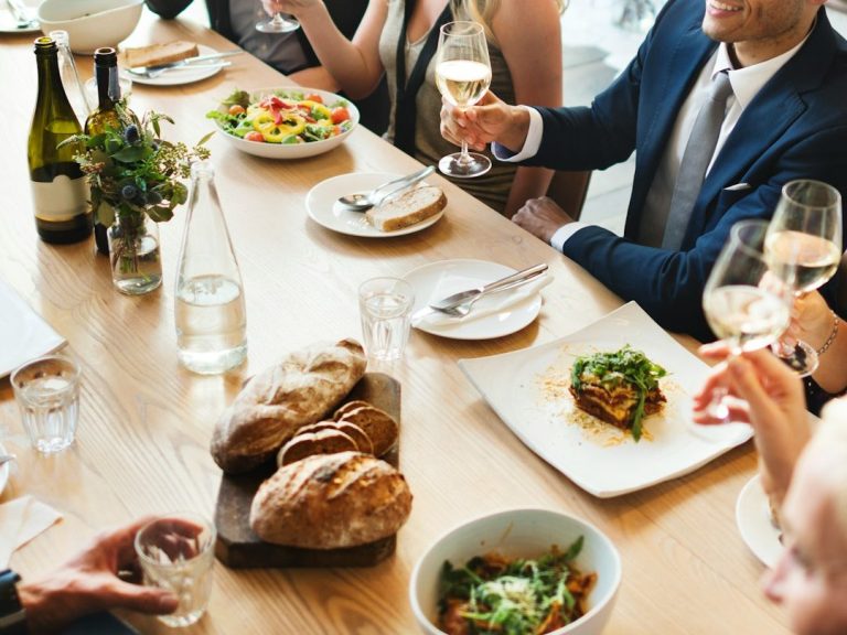 Dîner festif avec des convives, plats raffinés et verres levés en toast.